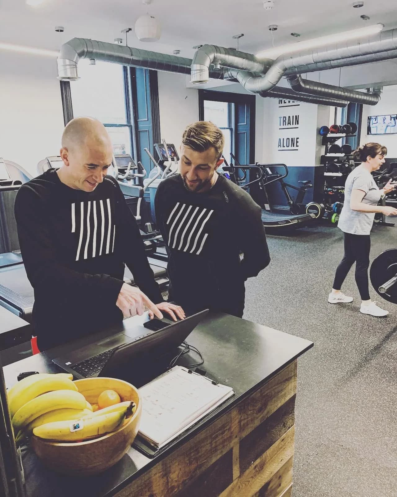 Ryan and a colleague looking at a laptop together at the front desk of the gym